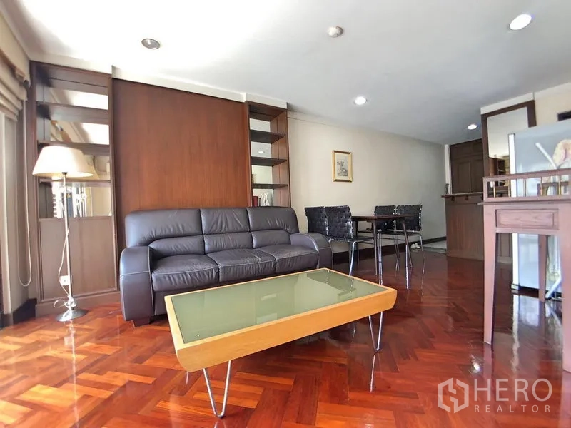 公寓 出租在Bang Rak, Bangkok - 客餐一体空间，皮沙发、餐桌椅、内置柜架与拼花木地板。