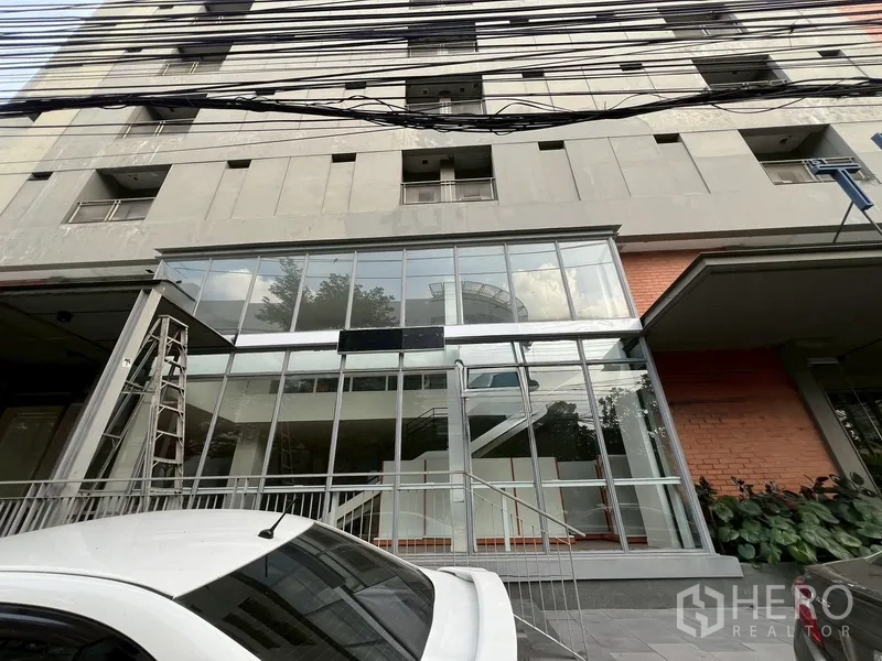 零售空间 出租在Watthana, Bangkok - 一层玻璃门面建筑外观，带台阶入口和前方停车位