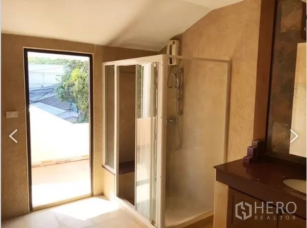 Detached House for sale in Saphan Sung, Bangkok - Bathroom with glass shower enclosure, vanity and door opening to a balcony area.