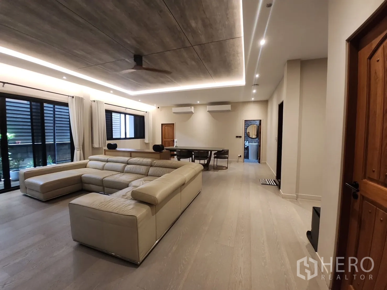 Detached House for rent in Bang Phli, Samut Prakan - Spacious living room with an L-shaped leather sofa, recessed lighting and wood flooring.