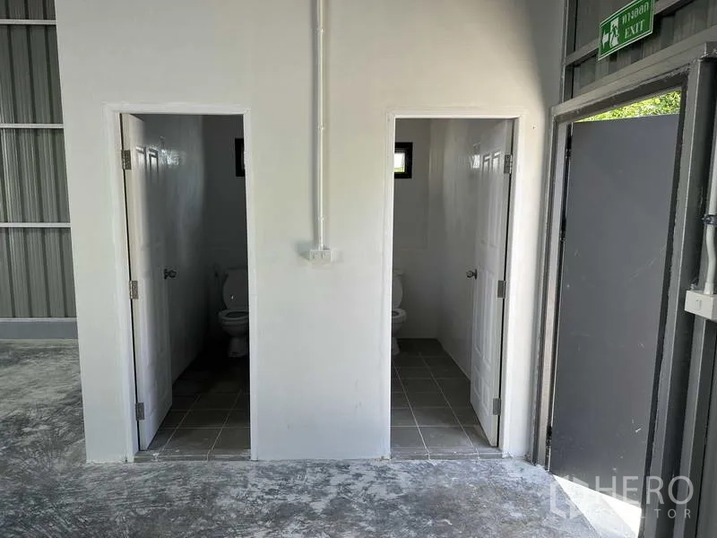 Warehouse for rent in Pak Kret, Nonthaburi - On-site washrooms inside the warehouse with tiled floors and white doors.