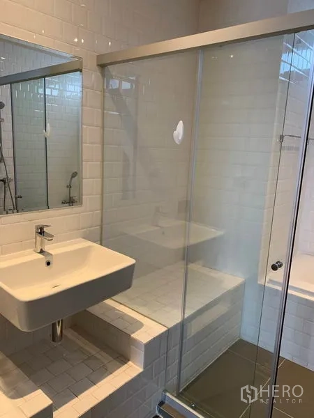 Condominium for rent in Watthana, Bangkok - Modern bathroom with wall mirror, square vanity and glass-enclosed shower with a tiled bench.