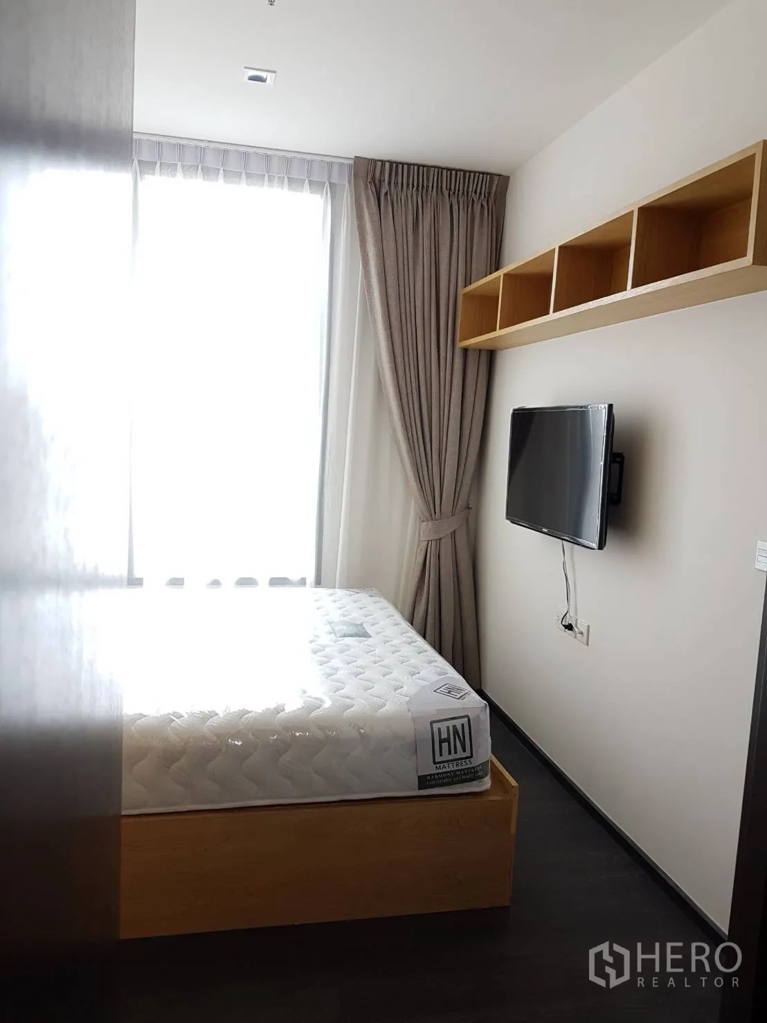 คอนโด ให้เช่าหรือขายในWatthana, Bangkok - ห้องนอนอบอุ่น เตียงยกพื้น ทีวีติดผนัง และหน้าต่างบานใหญ่พร้อมผ้าม่าน