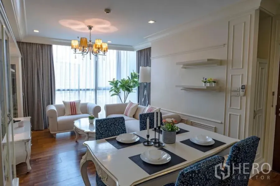 Condominium for rent in Watthana, Bangkok - Dining table set beside the living area with chandelier and wide windows bringing in natural light.