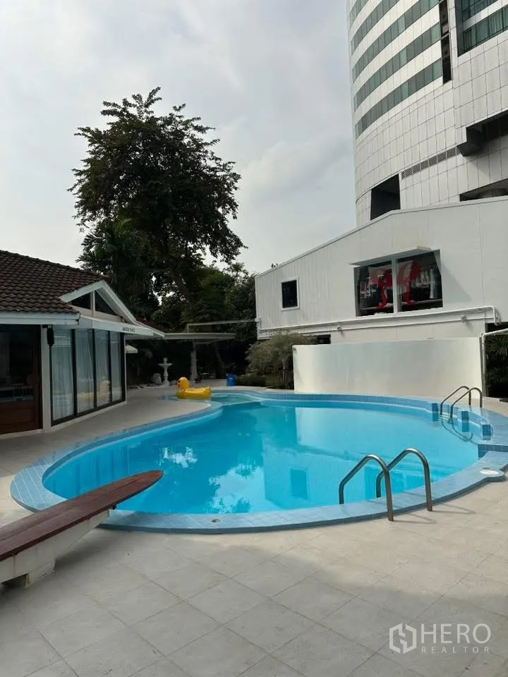 พื้นที่ขายของ for rent in Khlong Toei, Bangkok - สระว่ายน้ำทรงโค้งพร้อมบันไดสแตนเลสและลานกระเบื้องข้างอาคารเตี้ย