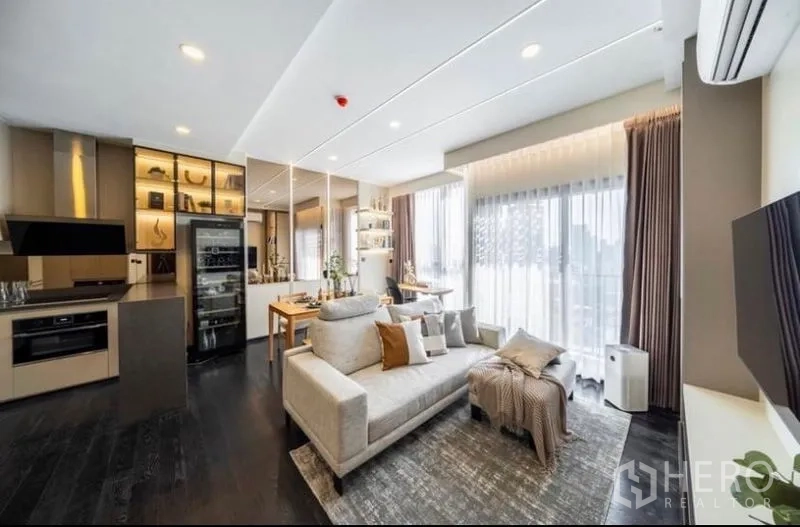 Condominium for sale in Watthana, Bangkok - Open-plan living area showcasing kitchen, sofa zone and bright balcony windows