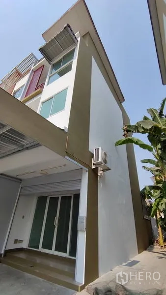 Townhouse for sale in Bang Khen, Bangkok - Modern three-storey townhouse exterior with carport and side windows.