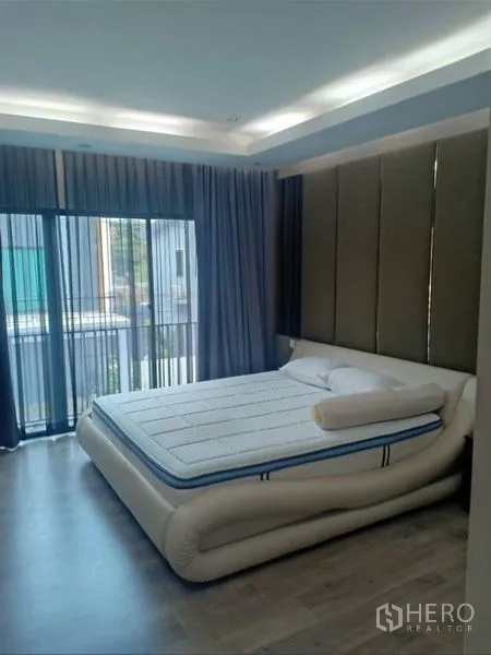 Detached House for rent in Thanyaburi, Pathum Thani - Sunlit bedroom with a modern bed, balcony access, and sheer and blackout curtains.