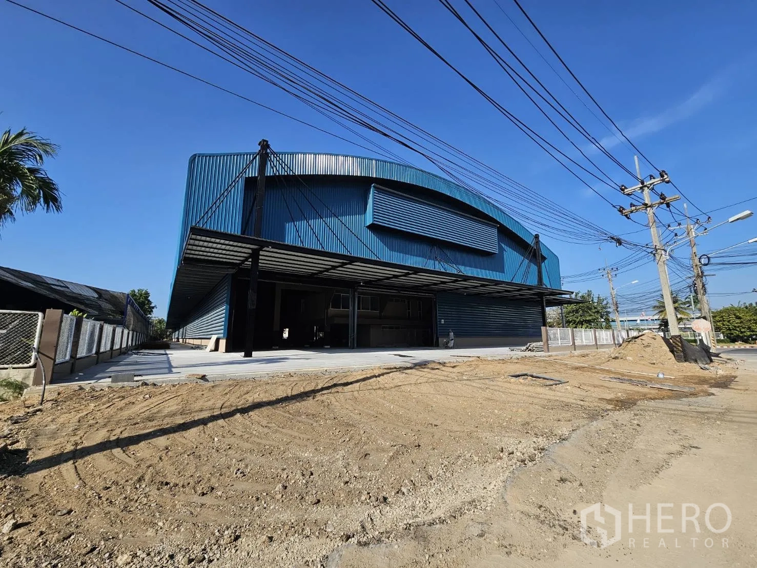 工厂 出租在Chon Buri - 面向道路的蓝色厂房立面，前场正在整平