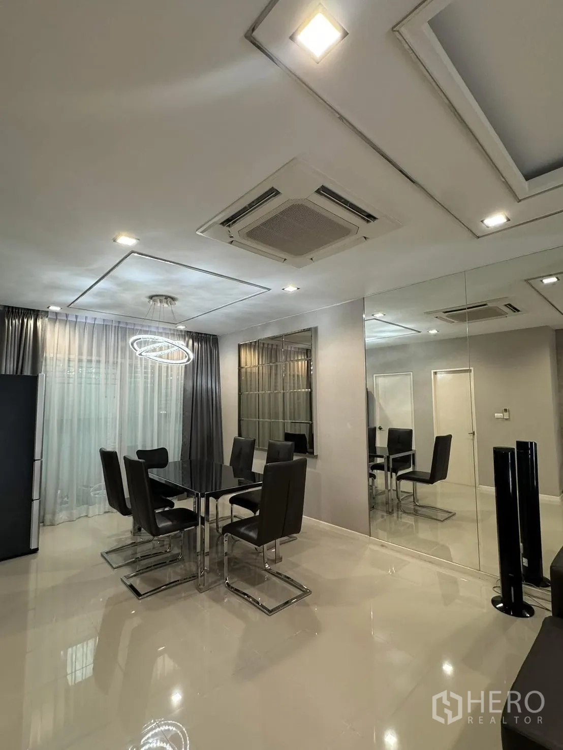 联排别墅 for rent in Suan Luang, Bangkok - 餐区配黑色玻璃餐桌、六把皮椅与环形吊灯。
