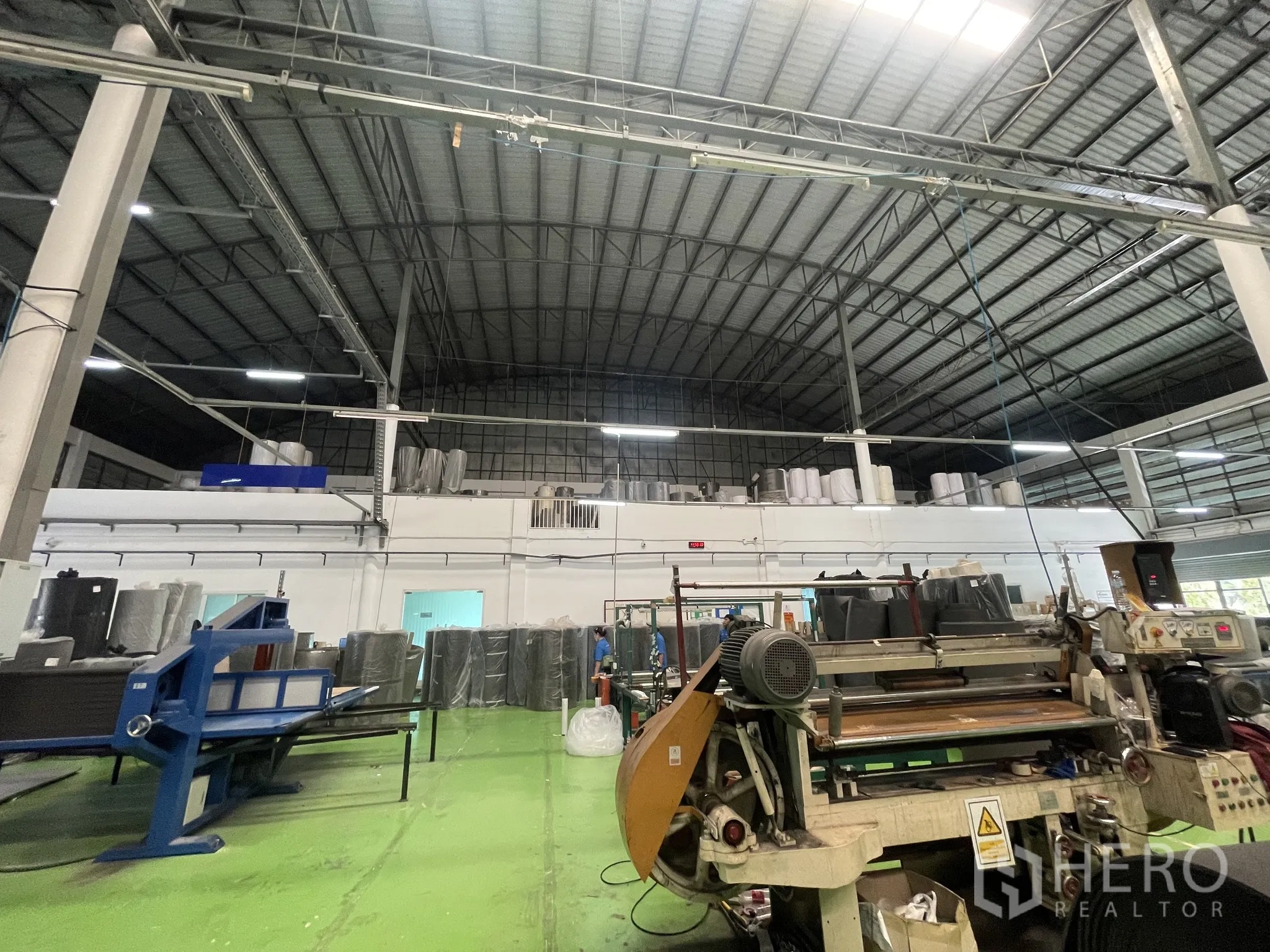 Warehouse for sale in Lat Lum Kaeo, Pathum Thani - Factory area with green epoxy floor, machines and mezzanine rooms beneath the tall roof.
