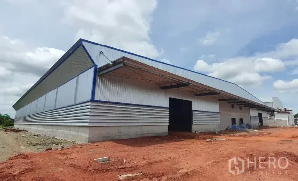 货栈 出租在Mueang Samut Sakhon, Samut Sakhon - 新建金属板外墙仓库外观，带装卸雨棚与宽阔场地，位于 Mueang Samut Sakhon。