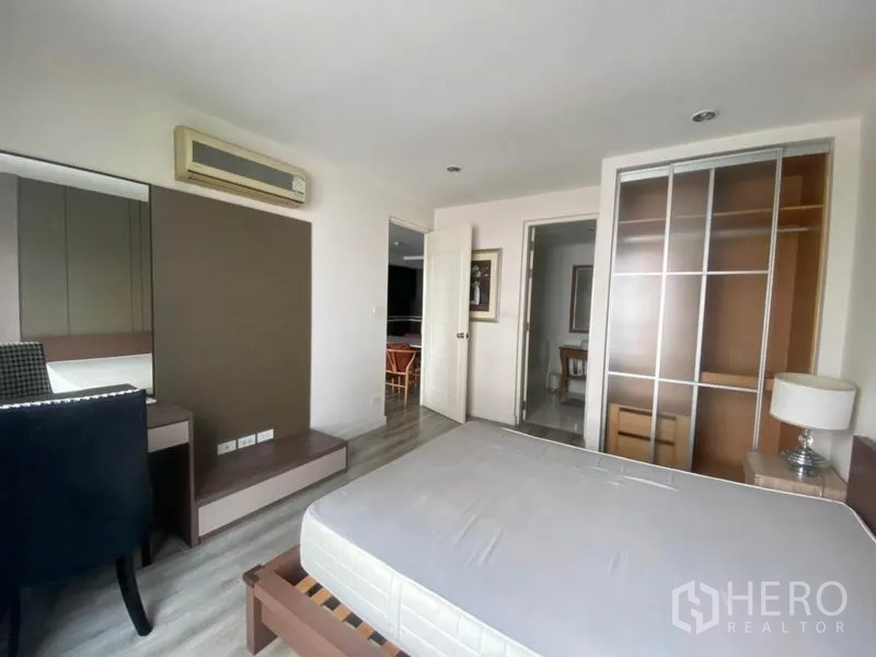 Condominium for rent in Watthana, Bangkok - Primary bedroom with built-in wardrobe, desk, and air-conditioning unit.