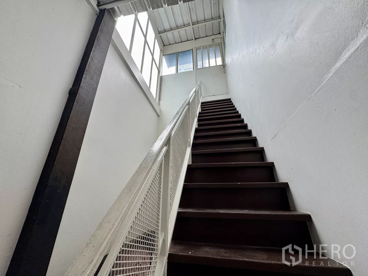 Shophouse for rent in Sathon, Bangkok - Staircase with white railing leading to a bright upper level.