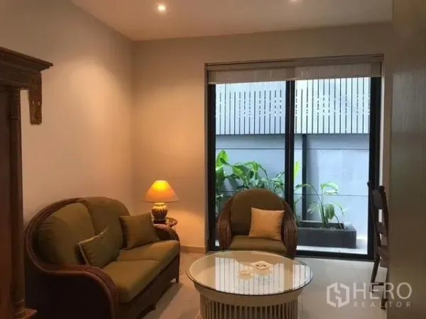 Townhouse for rent in Khlong Toei, Bangkok - Cozy sitting nook with rattan sofa set and a window facing a planter box.