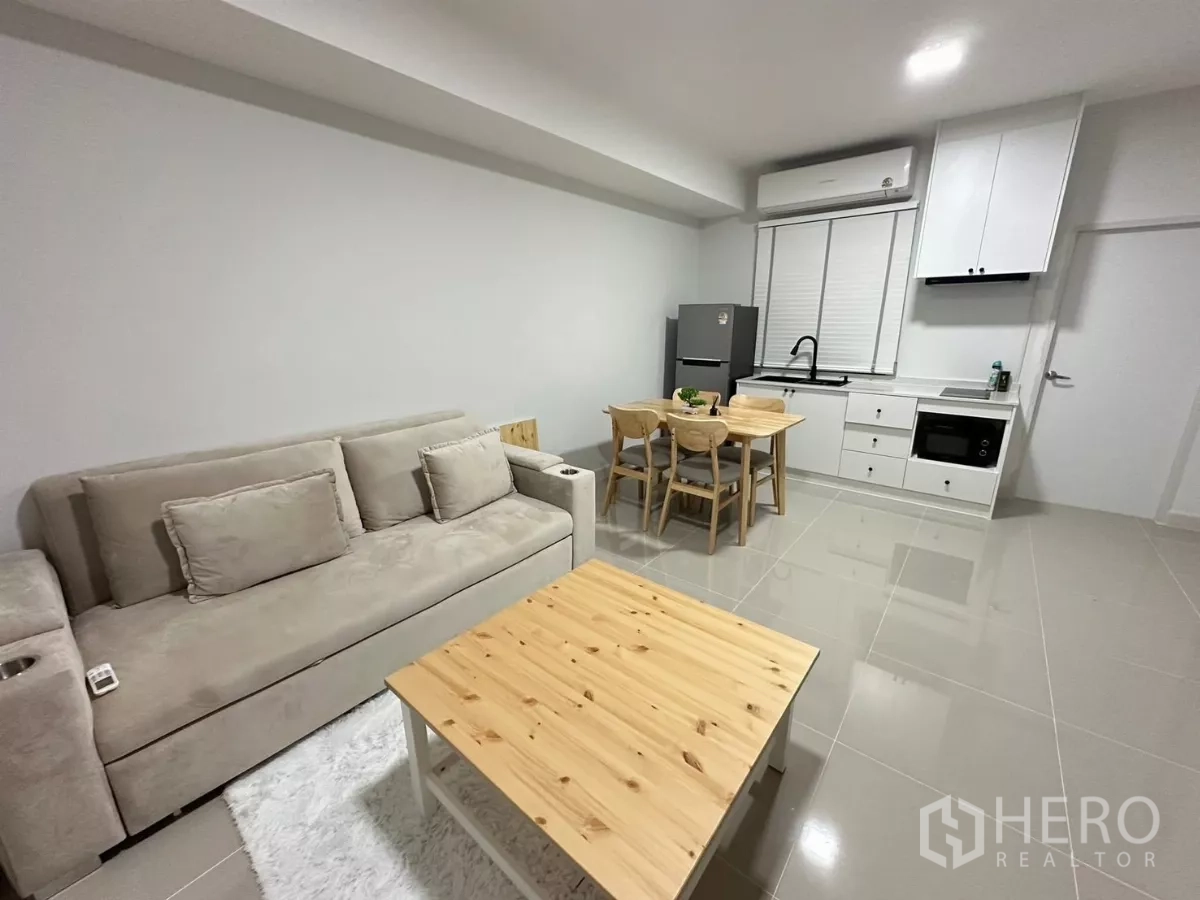 ทาวน์เฮาส์ ให้เช่าในBang Phli, Samut Prakan - พื้นที่นั่งเล่นแบบเปิดโล่ง พร้อมโต๊ะอาหาร 4 ที่ และครัวบิวท์อินสีขาว