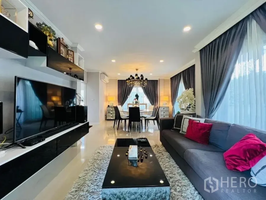 บ้าน ให้เช่าหรือขายในBang Khen, Bangkok - ห้องนั่งเล่นและรับประทานอาหารแบบเปิดโล่ง โคมระย้า ผ้าม่านสีเทา ทีวีจอใหญ่ และพื้นกระเบื้องเงา