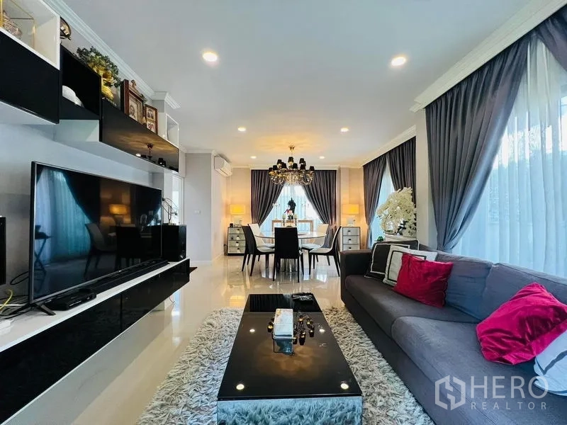 บ้าน ให้เช่าหรือขายในBang Khen, Bangkok - ห้องนั่งเล่นและรับประทานอาหารแบบเปิดโล่ง โคมระย้า ผ้าม่านสีเทา ทีวีจอใหญ่ และพื้นกระเบื้องเงา