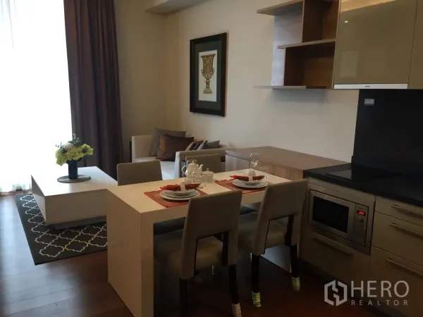 Condominium for rent or sale in Watthana, Bangkok - Open-plan living and dining area with fitted kitchenette and built-in cabinets.