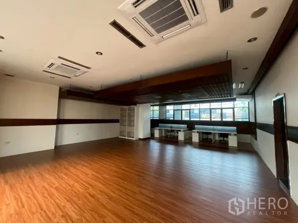 พื้นที่ขายปลีก ให้เช่า - ฮอลล์ค้าปลีกกว้าง พื้นไม้ ฝ้าลงคาน โครงชั้นวาง และหน้าต่างบานยาว