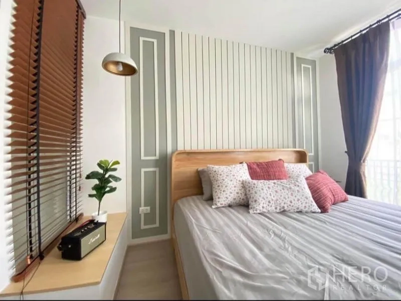 联排别墅 出租在Prawet, Bangkok - 明亮卧室，竖条装饰墙，大窗，木床与吊灯。