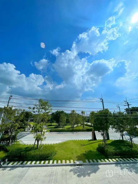 Townhouse for rent in Bang Phli, Samut Prakan - Green community view with manicured lawn, trees and wide road.