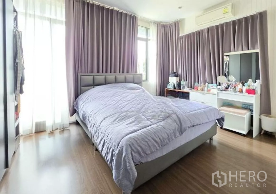 Detached House for sale in Bang Kapi, Bangkok - Secondary bedroom with wide windows, lilac curtains, vanity and wood flooring.