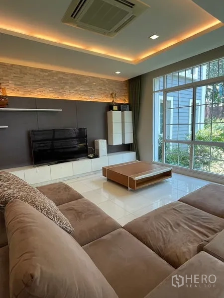 独立式住宅 出租在Bang Phli, Samut Prakan - 客厅电视背景墙，氛围灯与转角沙发