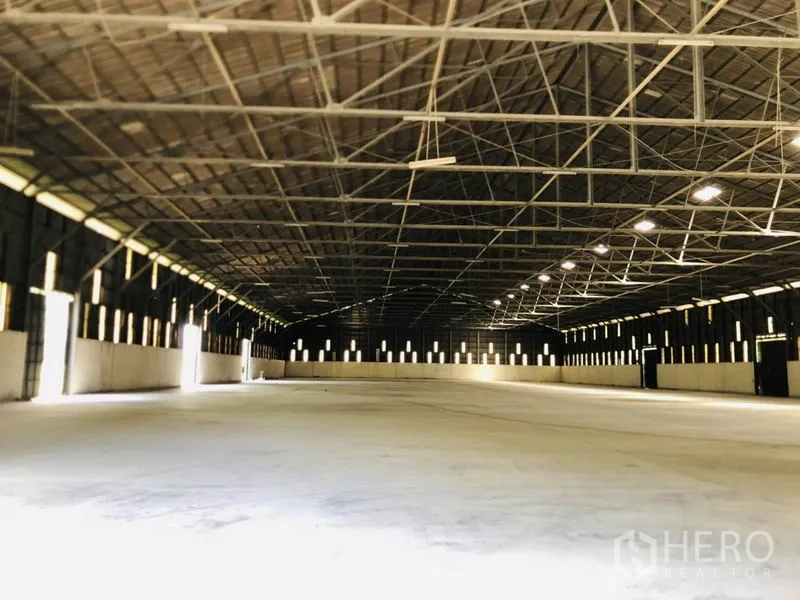 Warehouse for rent in Nonthaburi - Wide interior view of the warehouse showing steel trusses and loading doors.
