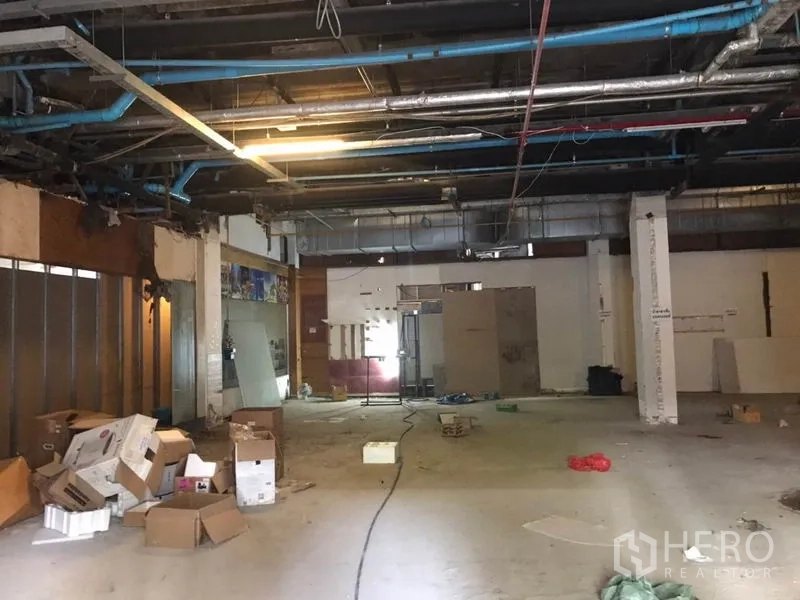 零售空间 出租在Khlong Toei, Bangkok - 大型毛坯商铺内部，层高可观，裸露风管与管道，地面有纸箱与材料，适合二次装修。
