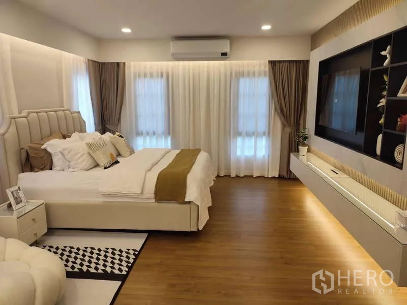 Detached House for rent in Bang Phli, Samut Prakan - Large master bedroom with king bed, built-in TV wall and wood floors.