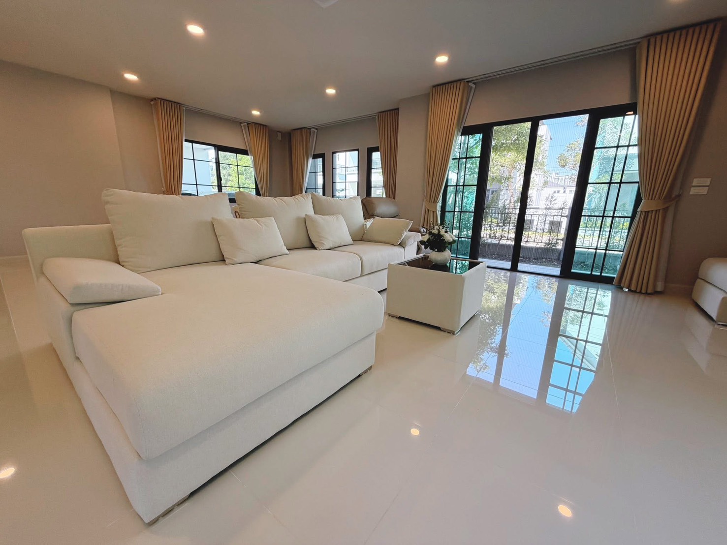 独立式住宅 出租在Bang Phli, Samut Prakan - 开放式客餐厅，L 形沙发，亮面地砖，推拉门通向露台。