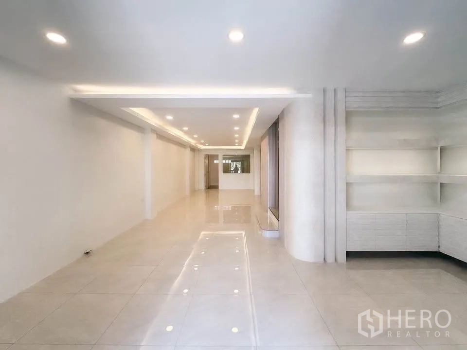 联排别墅 for sale in Wang Thonglang, Bangkok - 宽敞瓷砖大厅，跌级吊顶与展示架一角。