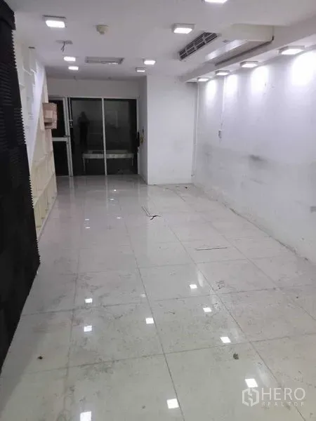 พื้นที่ขายปลีก ให้เช่าในWatthana, Bangkok - พื้นที่ค้าปลีกชั้นล่าง ปูพื้นกระเบื้องสีขาว ไฟดาวน์ไลท์ และประตูกระจกด้านหลัง