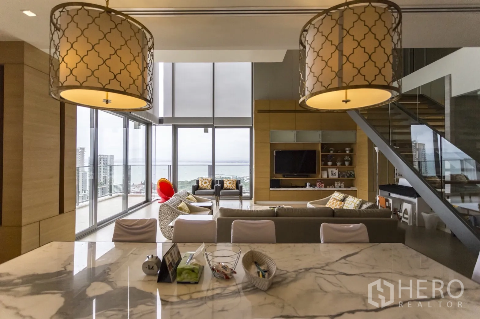 Condominium for rent in Bang Lamung, Chon Buri - Open-plan living area with marble island kitchen, floor-to-ceiling windows, and ocean view.