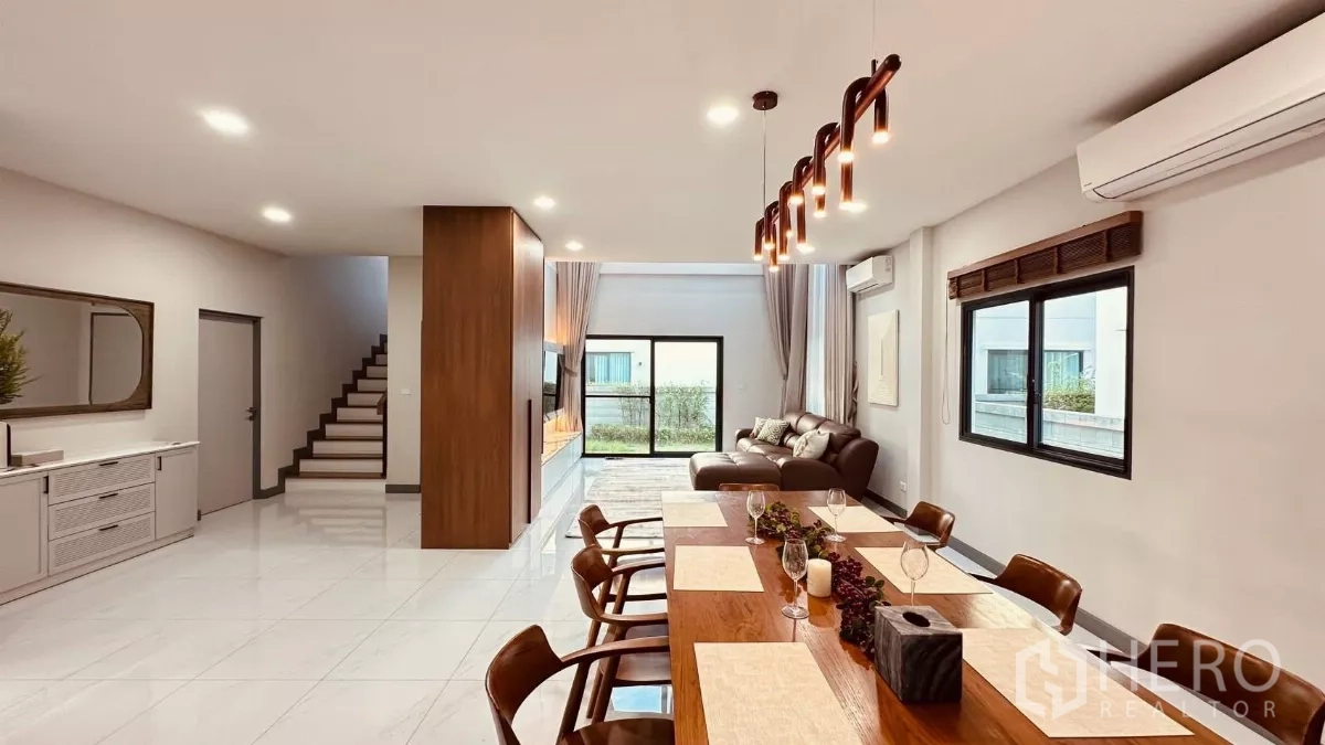 Detached House for rent in Bang Phli, Samut Prakan - Long view of the open living–dining area with statement pendant lights and a staircase.