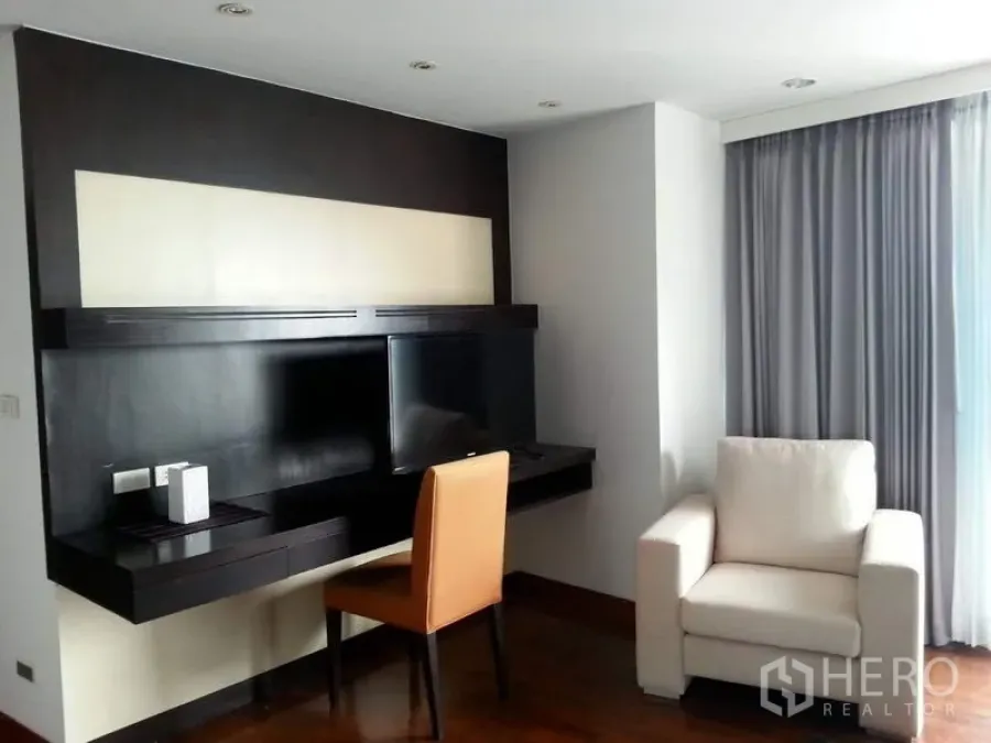 公寓 出租或出售在Pathum Wan, Bangkok - 客厅带悬空电视墙与书桌、单人沙发及落地窗帘。