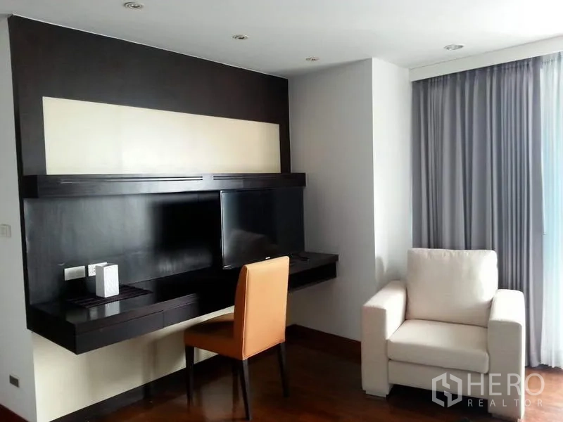 公寓 出租或出售在Pathum Wan, Bangkok - 客厅带悬空电视墙与书桌、单人沙发及落地窗帘。