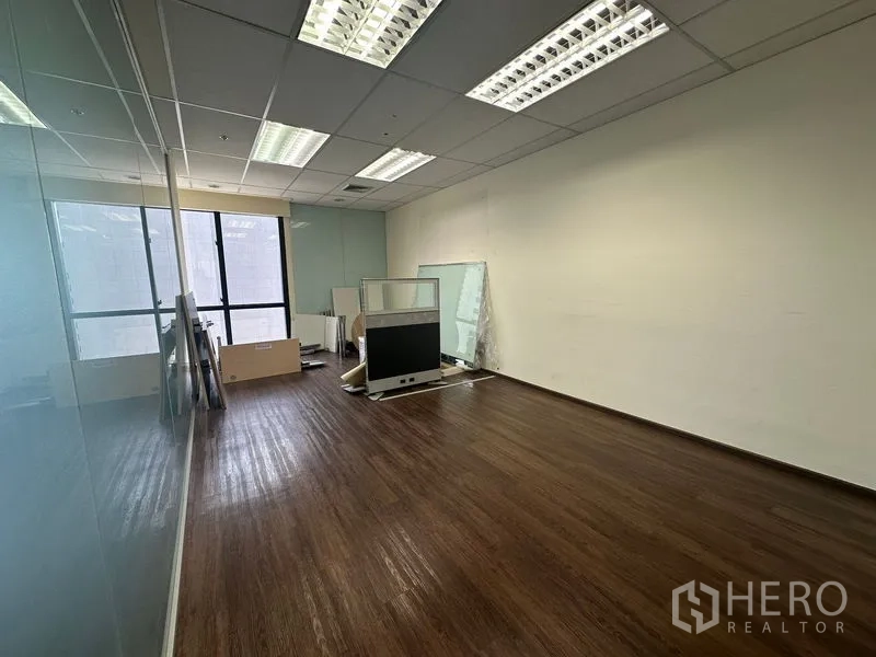 办公空间 出租在Bang Rak, Bangkok - 空置办公室，玻璃墙、木地板与存放的隔断件。