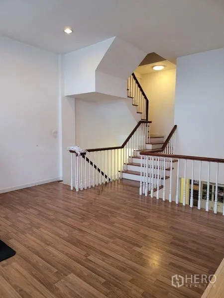 联排别墅 出售在Bang Kapi, Bangkok - 楼梯平台，白色扶手与木地板的转角楼梯。