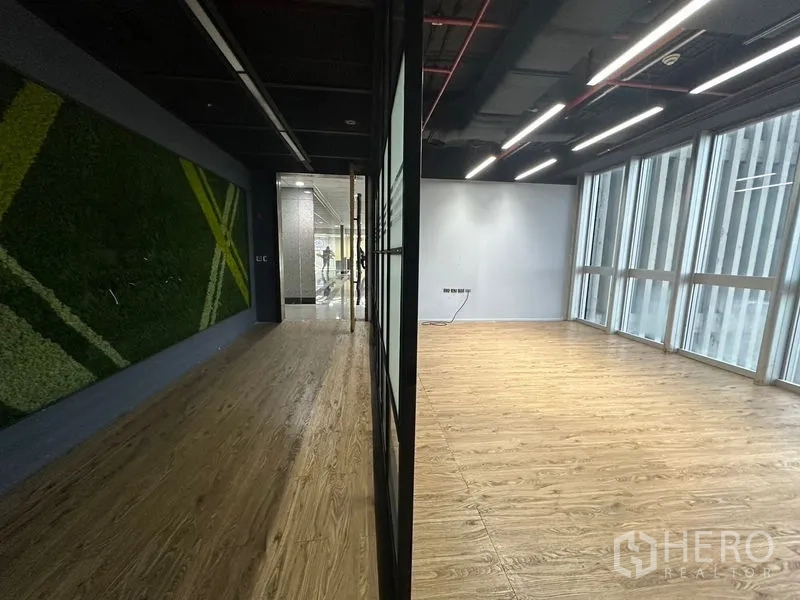 Office Space for rent in Bang Rak, Bangkok - View showing corridor with green wall contrasted with a bright windowed room divided by glass.