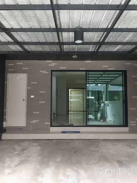 联排别墅 出租在Mueang Samut Prakan, Samut Prakan - 带顶车棚与推拉玻璃入户门的联排别墅前区。