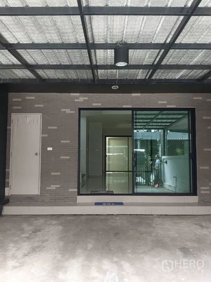 联排别墅 出租在Mueang Samut Prakan, Samut Prakan - 带顶车棚与推拉玻璃入户门的联排别墅前区。