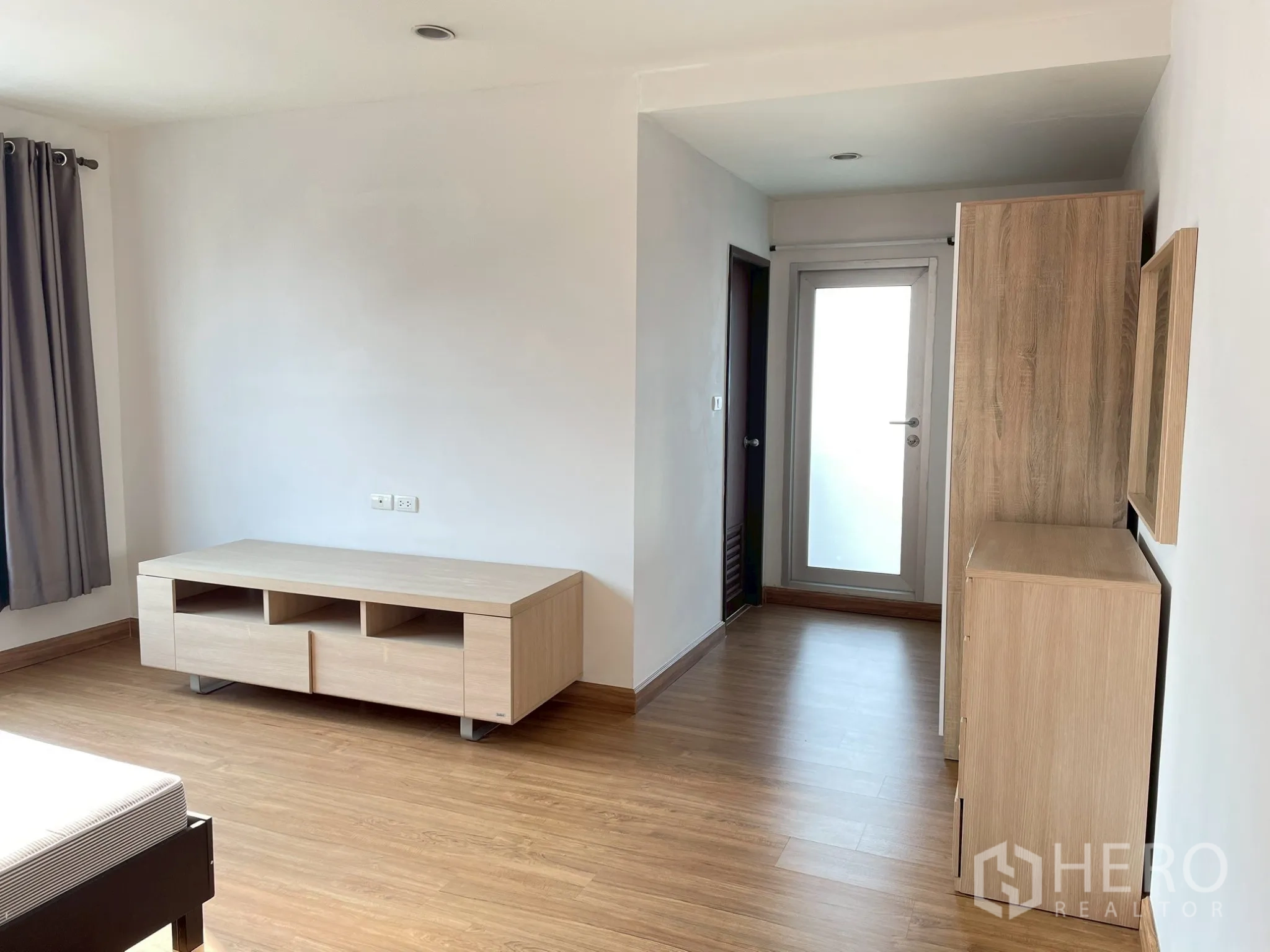 Apartment for rent in Khlong Toei, Bangkok - Bedroom corner with low media cabinet and frosted glass door.