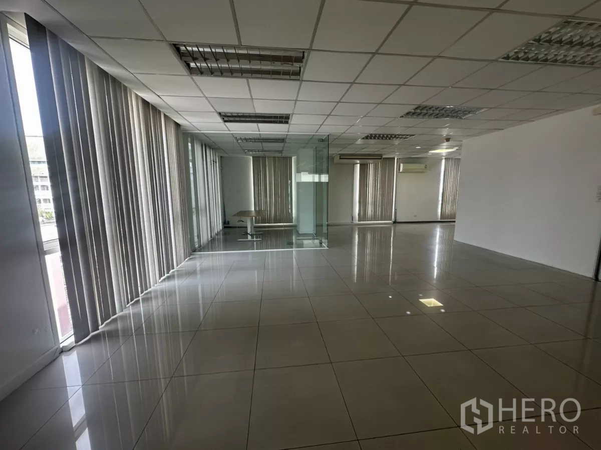 Office Space for rent in Huai Khwang, Bangkok - Open office area with glass walls, recessed lighting and tall windows with blinds.