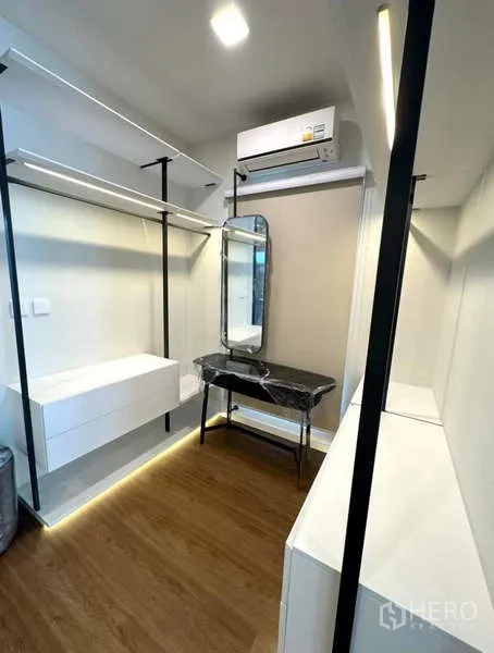 Detached House for rent in Samut Prakan - Bright walk-in closet with vanity, open shelves and wood flooring.