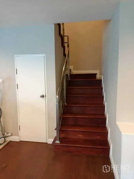 Condominium for rent or sale in Huai Khwang, Bangkok - Internal wooden staircase with stainless steel handrail and storage door.