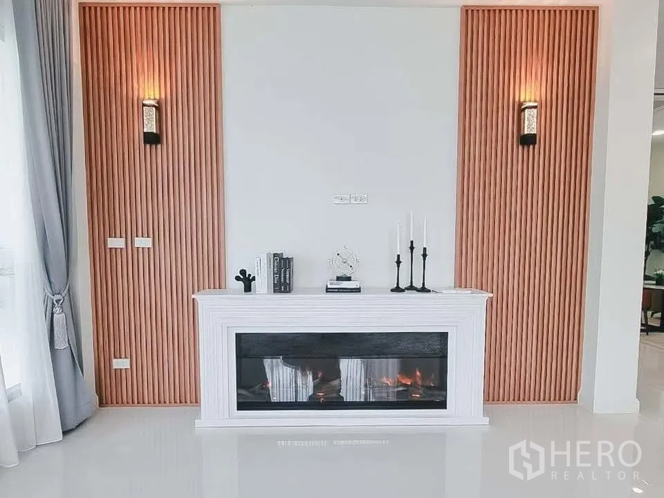 Detached House for rent or sale in Bang Phli, Samut Prakan - White decorative electric fireplace centered on a feature wall with vertical wood panels.