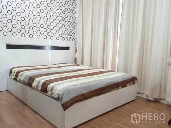 公寓 出租在Ratchathewi, Bangkok - 明亮卧室，条纹床品与白色床架，圆点特色墙，落地窗帘与木地板。