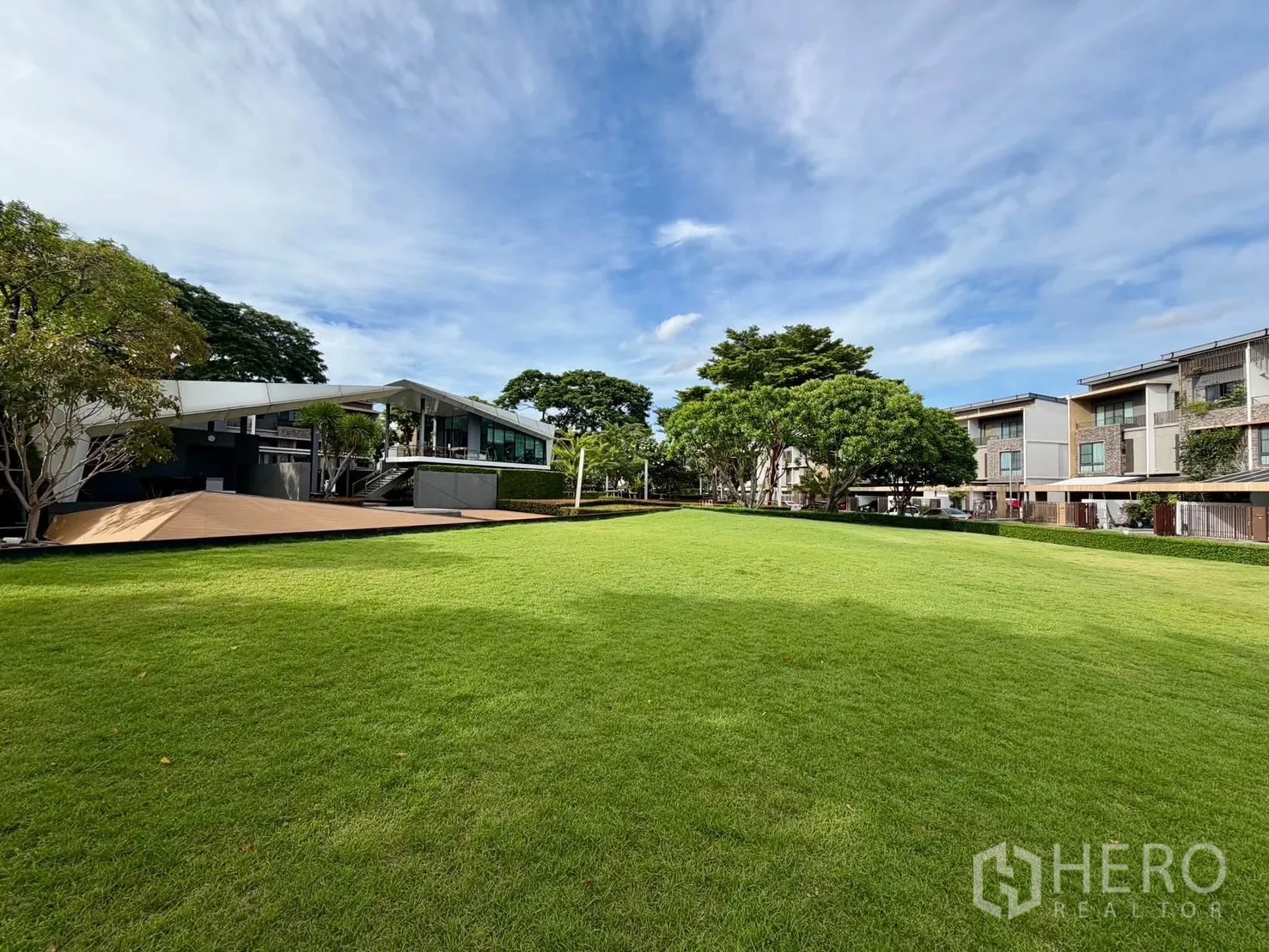 Townhouse for rent in Lat Phrao, Bangkok - Expansive communal lawn with modern clubhouse and row of townhouses.